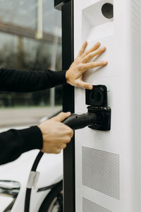 Man holding electric cord at charging station