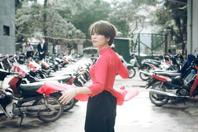 Beautiful young woman standing on street against motorcycles