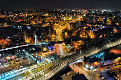 High angle view of illuminated street amidst buildings in city at night