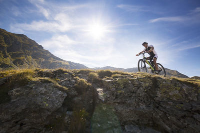 Low angle view of mountain biker riding bicycle against sky