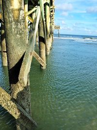 Pier on sea against cloudy sky