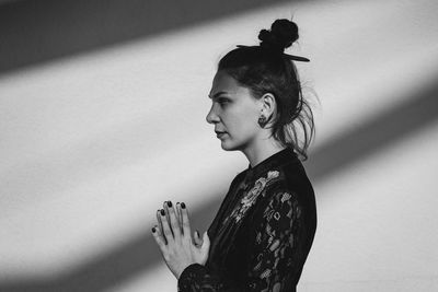 Young woman looking away against wall