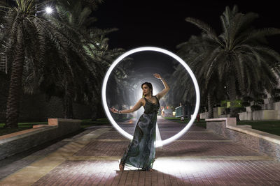 Woman standing by palm trees at night