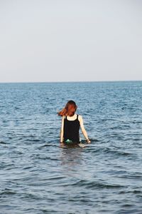 Rear view of woman in sea against clear sky
