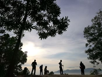 Silhouette people standing by tree against sky during sunset