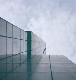 Directly below shot of modern glass building against cloudy sky