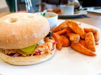 Burger with prepared potatoes served in plate on table