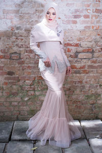 Portrait of woman standing against brick wall