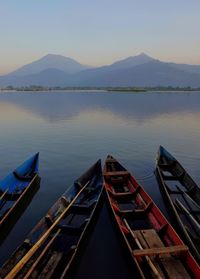 Boats moored at lake during sunset