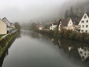 River amidst houses and buildings against sky