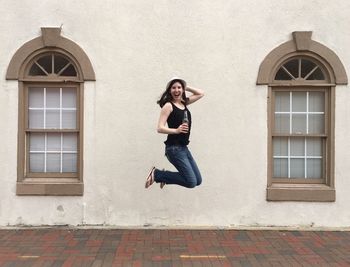 Portrait of happy woman jumping against wall