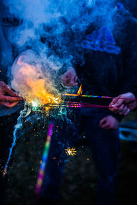 Cropped hands burning sparklers