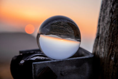 Close-up of old metal against sea during sunset