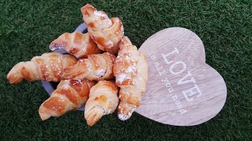Close-up of croissants in container by text on heart shape over field