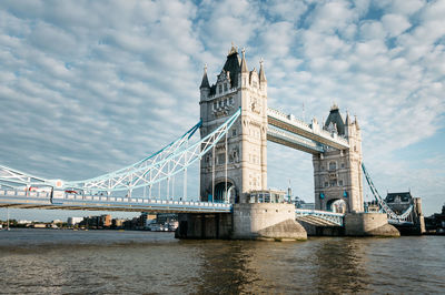 Bridge over river against cloudy sky