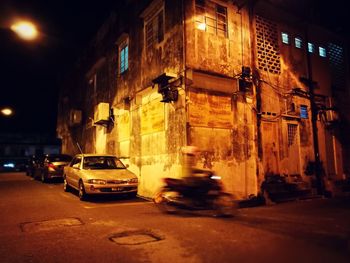 Cars on illuminated street in city at night