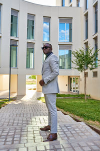 African-american businessman between buildings, with the sun on his back person