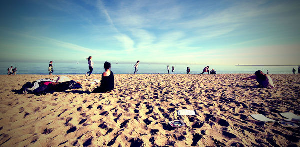 People sitting on beach against sky