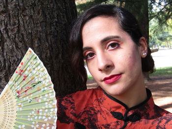 Close-up portrait of young man against tree trunk