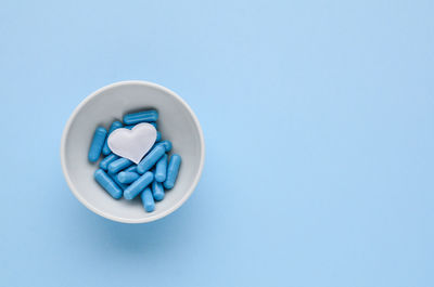 Directly above shot of pills spilling from bottle against blue background