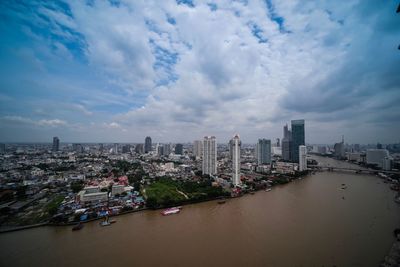 Aerial view of city buildings against cloudy sky