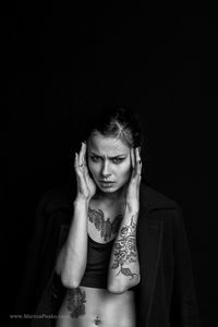 Portrait of young woman against black background