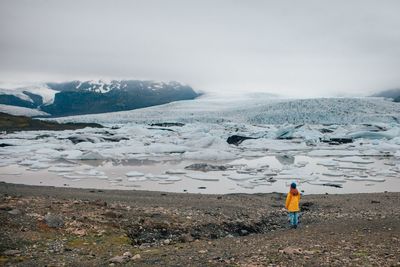 Man standing on frozen beach against sky