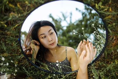 Reflection of a young asian girl in a mirror in nature
