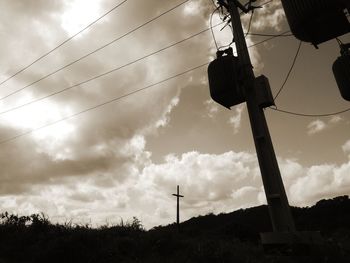 Low angle view of silhouette electricity pylon on field against sky