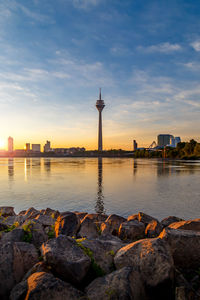 View of river and buildings against sky during sunset