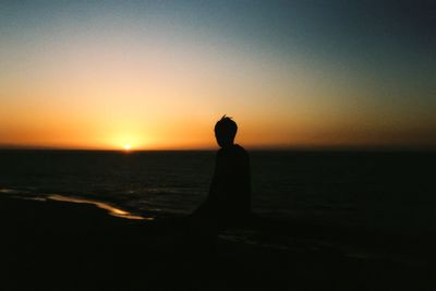 Silhouette of people standing on beach at sunset