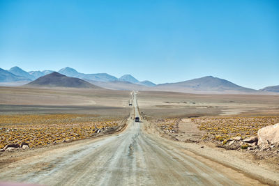 Road leading towards desert against clear sky