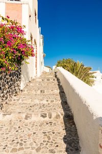 Footpath amidst buildings against clear blue sky