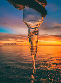 Close-up of water on beach against sky during sunset