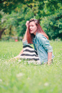 Beautiful young woman on grass in field