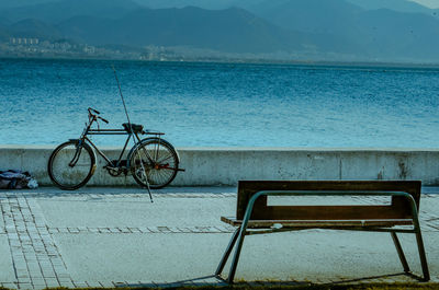 Bicycle on bench by sea against sky