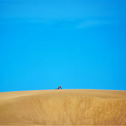 Low angle view of man walking on roof against clear blue sky