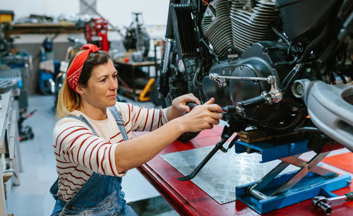 Mechanic woman reviewing motorcycle over platform