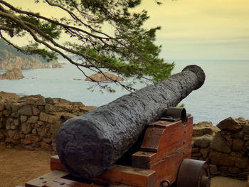 Cannon at fortress by sea against sky during sunset