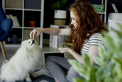 Woman feeding dog at home