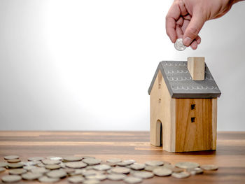 Close-up of hand holding coins on wooden table