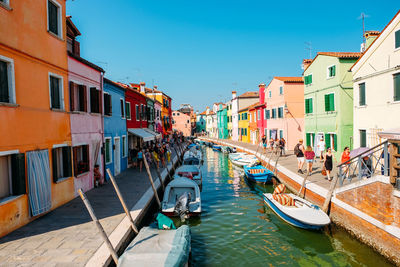 Boats moored in canal amidst buildings in city against sky