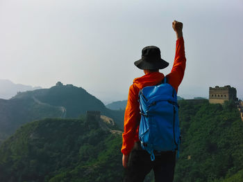 Male hiker with hand raised standing against great wall of china