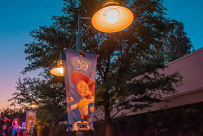 Low angle view of illuminated lighting equipment on street at dusk