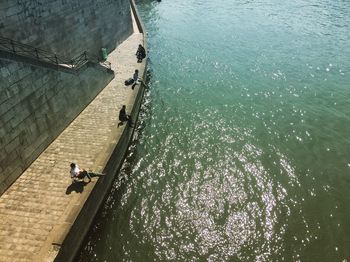 High angle view of people sitting on pier by sea