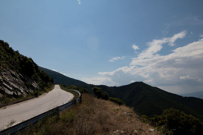 Scenic view of road by mountains against sky