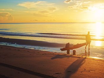 Silhouette of people on beach at sunset