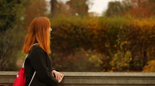 Woman standing by railing against trees