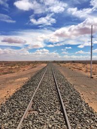 Surface level of railroad track against cloudy sky