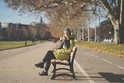 Full length portrait of man sitting on seat in park